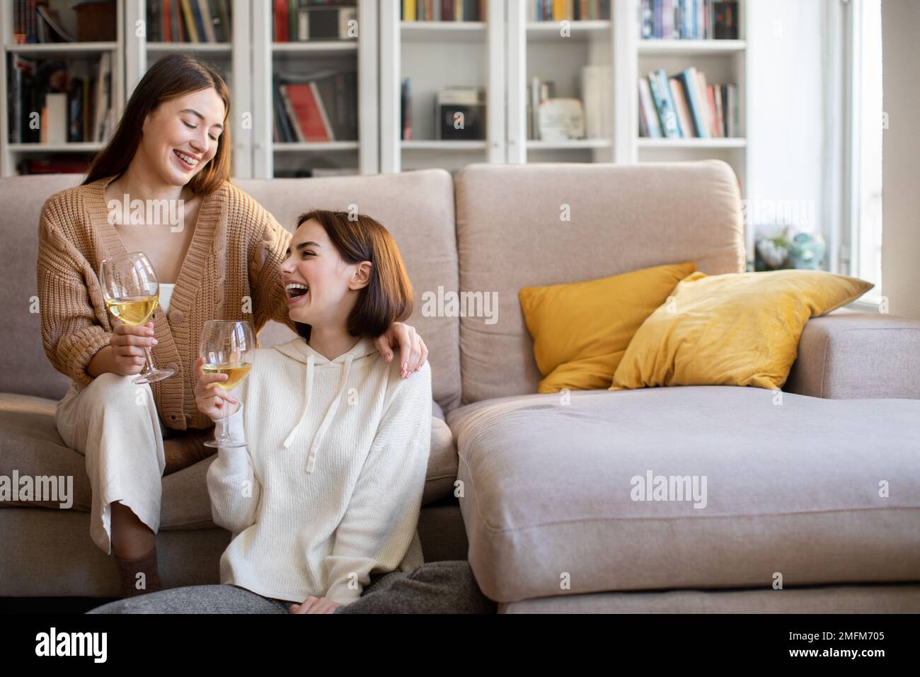 Zufriedene europäische Millennials-Freunde jubeln Gläser Wein an, erholen sich in der Freizeit Klatsch und Tratsch, feiern Urlaub Stockfoto