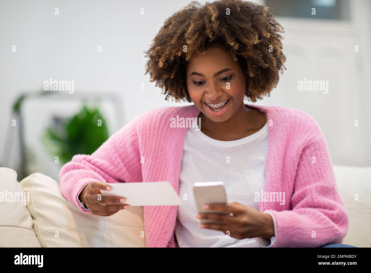 Emotionale junge Frau, die zu Hause auf der Couch ruht und ein Smartphone benutzt Stockfoto