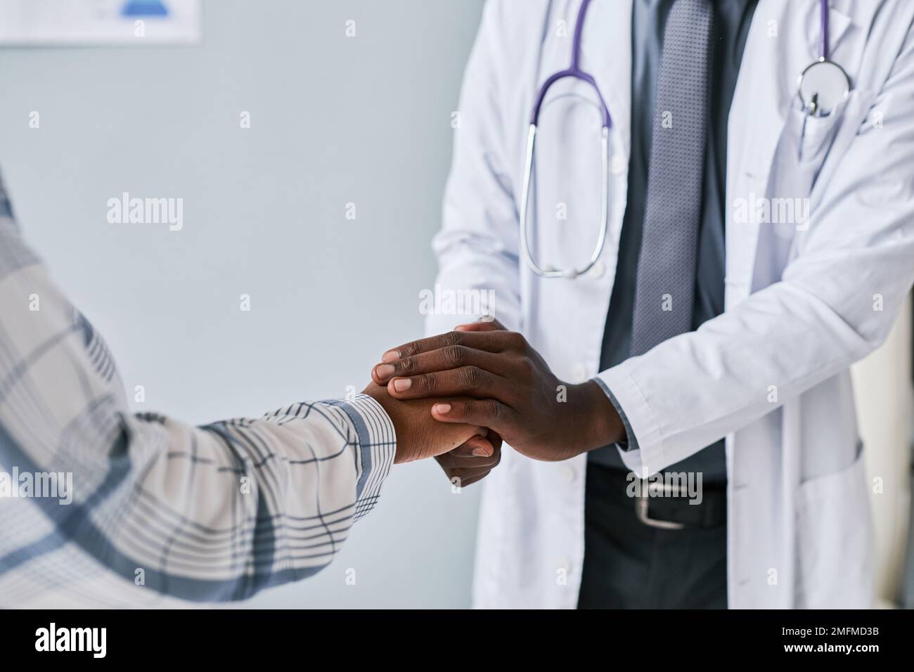 Nahaufnahme eines pflegenden schwarzen Arztes, der mit der Patientin Hand hält, um sie zu stützen und zu beruhigen Stockfoto