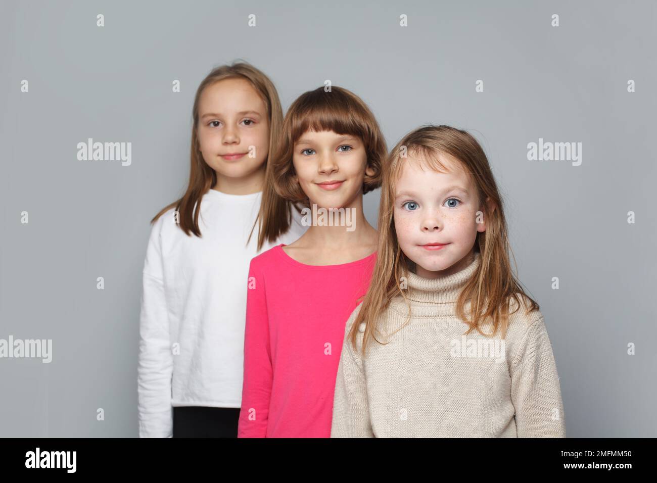 Kinder im Alter von 7, 8 und 9 Jahren. Junge Mädchen mit grauem Hintergrund Stockfoto