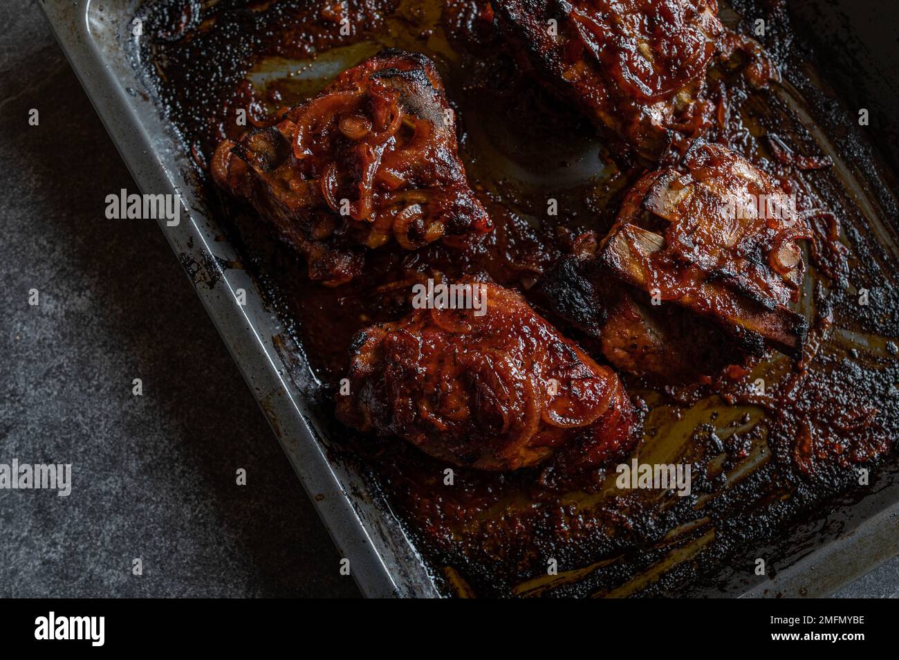 Grillrippchen auf einem Backblech, isoliert auf dunklem Hintergrund. Draufsicht Stockfoto