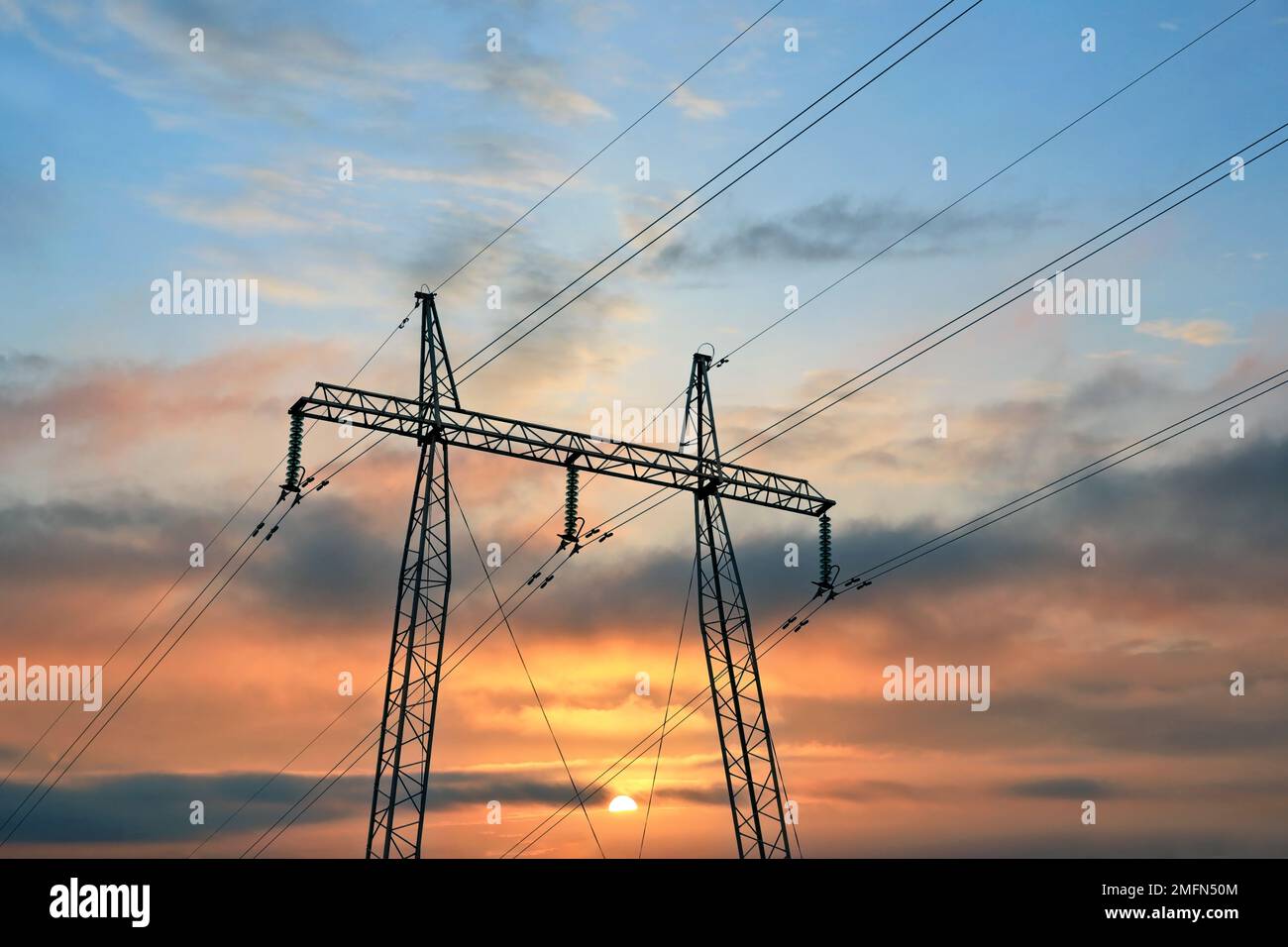 Strompylon und Übertragungsleitungen gegen den Sonnenaufgang. Stockfoto
