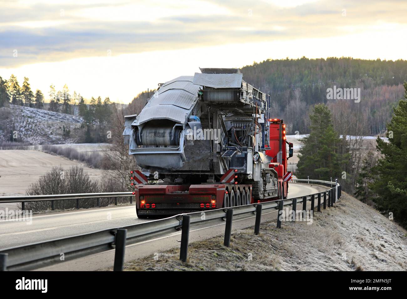 Quetsch- und Siebausrüstung, die von einem Auflieger als Überladung entlang der Autobahn transportiert wird. Salo, Finnland. 20. Januar 2022. Stockfoto