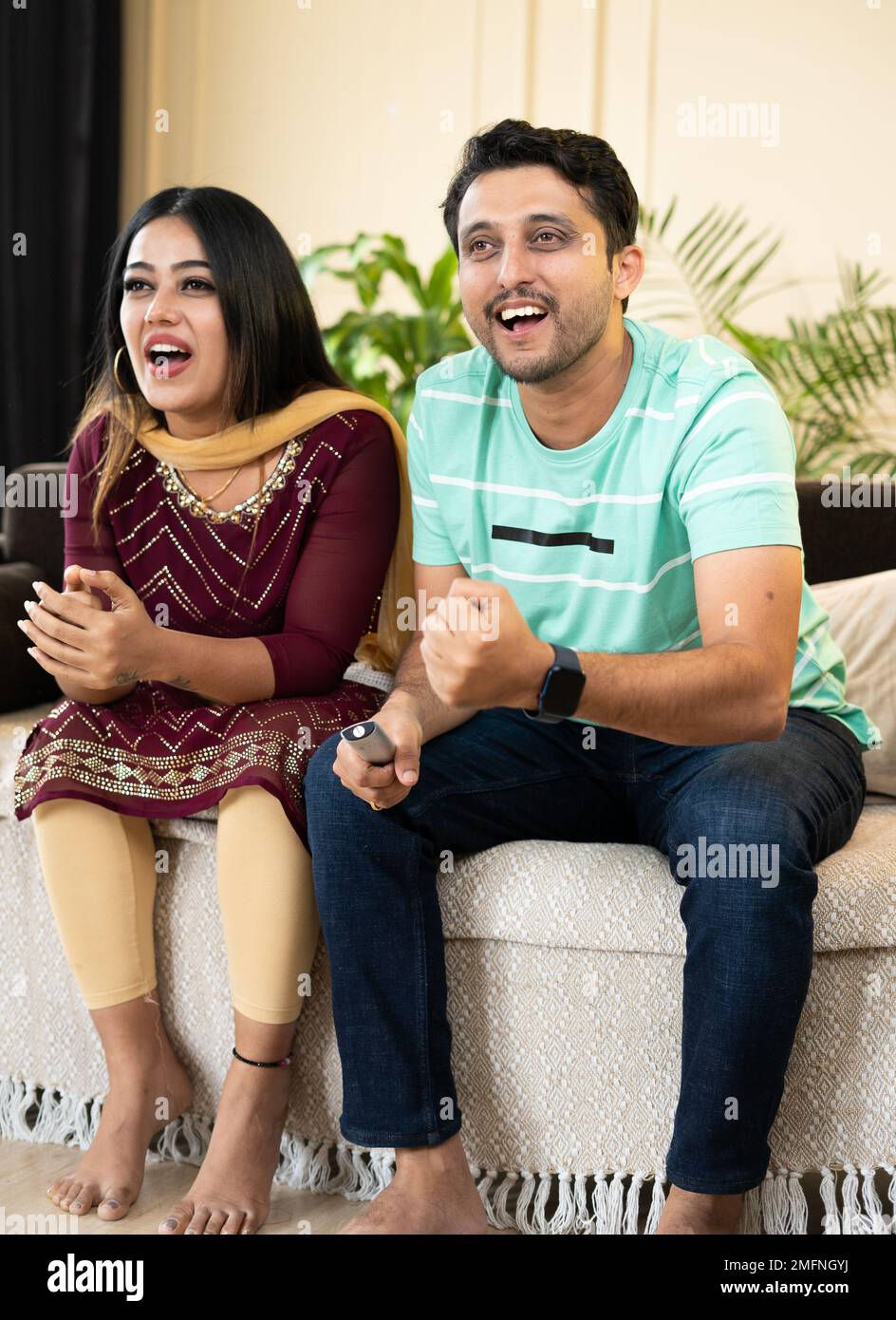 Vertikale Vollaufnahme des aufgeregten, fröhlichen Paares, das zu Hause ein Live-Cricket-Sportspiel im fernsehen oder Fernsehen ansieht - Konzept der Unterhaltung Stockfoto