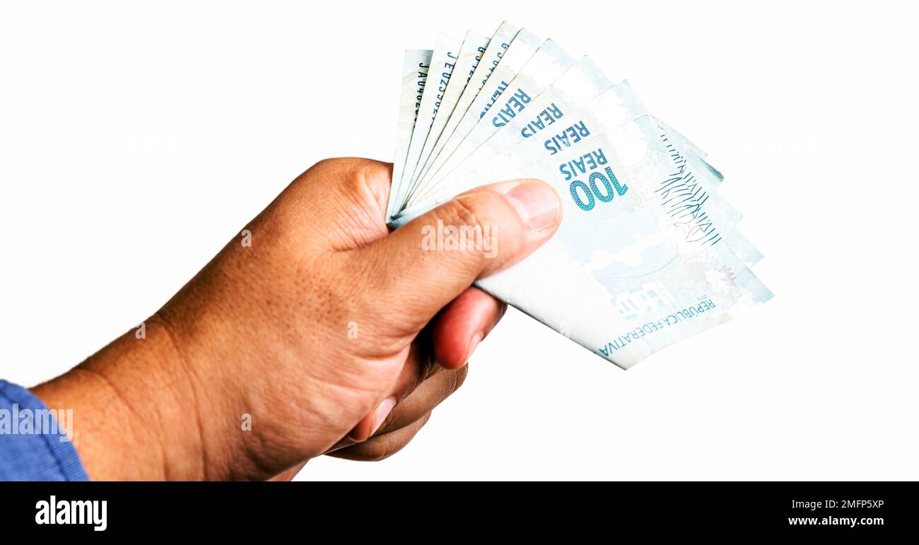 Banknoten von hundert Reais aus brasilien, Tag der Sozialleistungszahlung. 100 Reais werden von männlicher Hand geliefert, Soforthilfe von der Regierung. Stockfoto