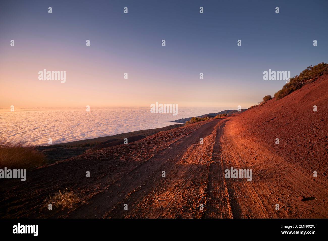 Unbefestigte Straße in Bergen über Wolken bei wunderschönem Sonnenuntergang. Teneriffa, Kanarische Inseln. Stockfoto