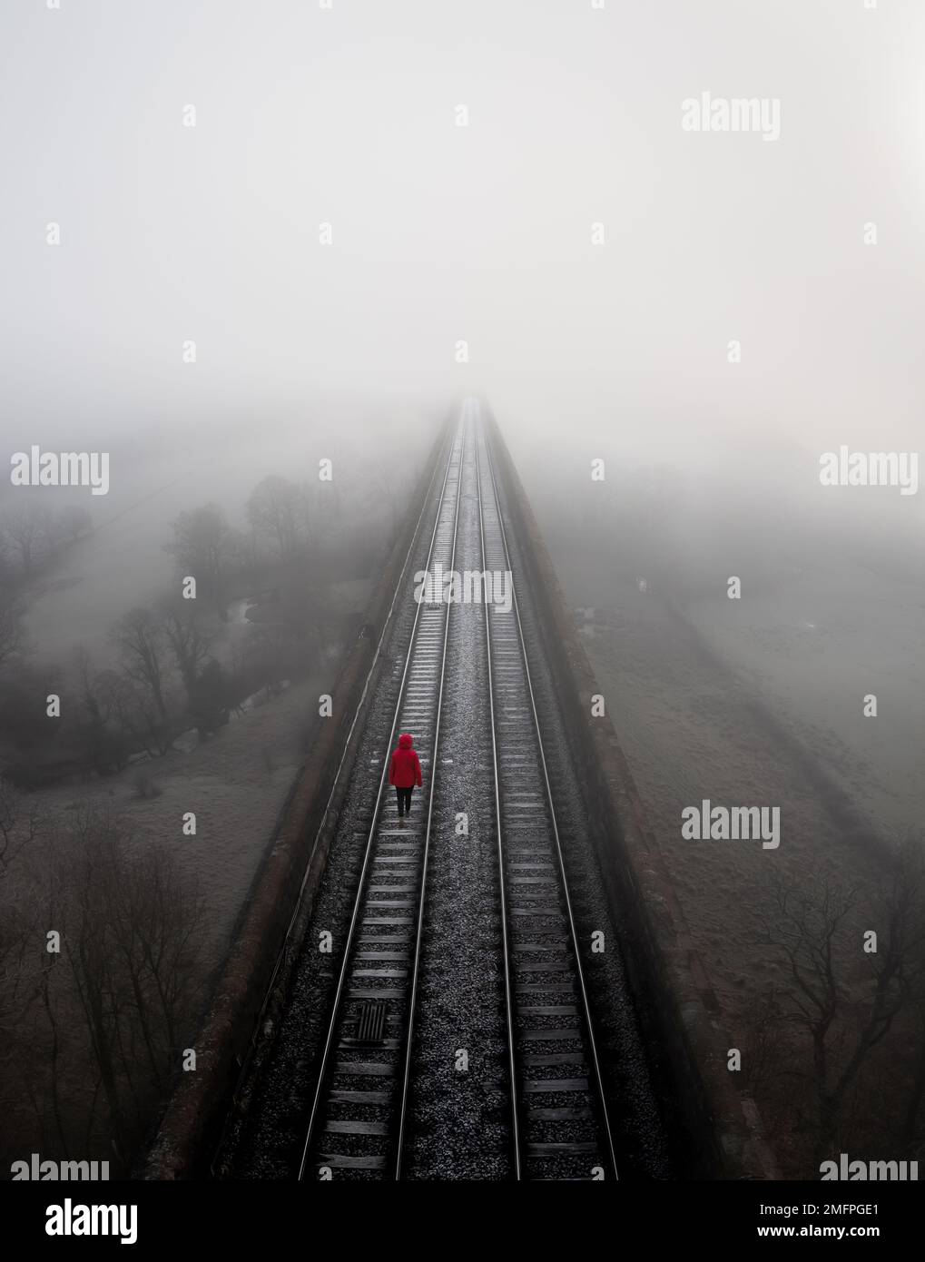 Luftlandschaft von Bahngleisen, die in die Ferne verschwinden, mit einem selbstmörderischen Depressiven, der verzweifelt läuft Stockfoto