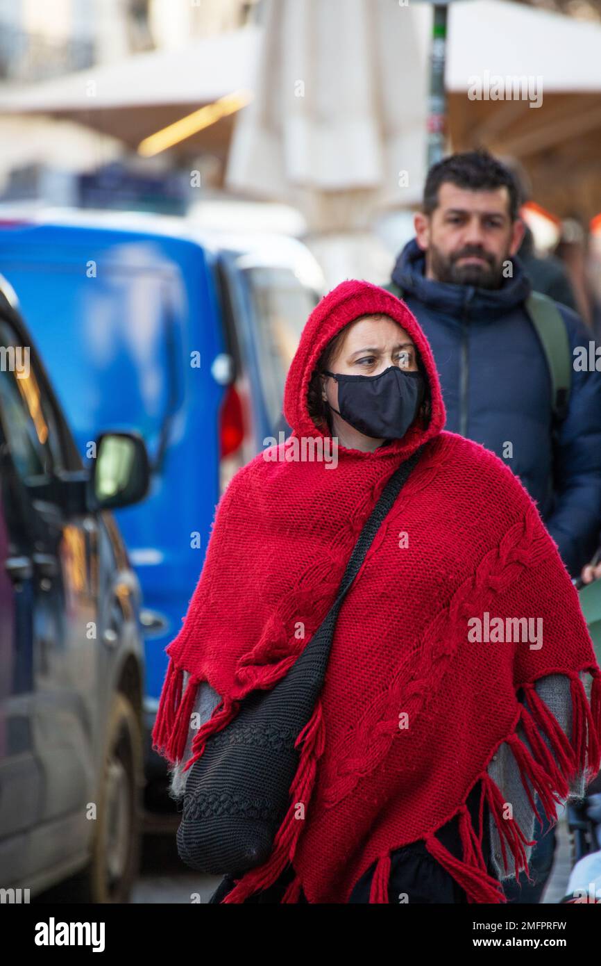Frau mit traditioneller Winterkleidung und Schutzmaske geht durch die Straßen von Lissabon Stockfoto
