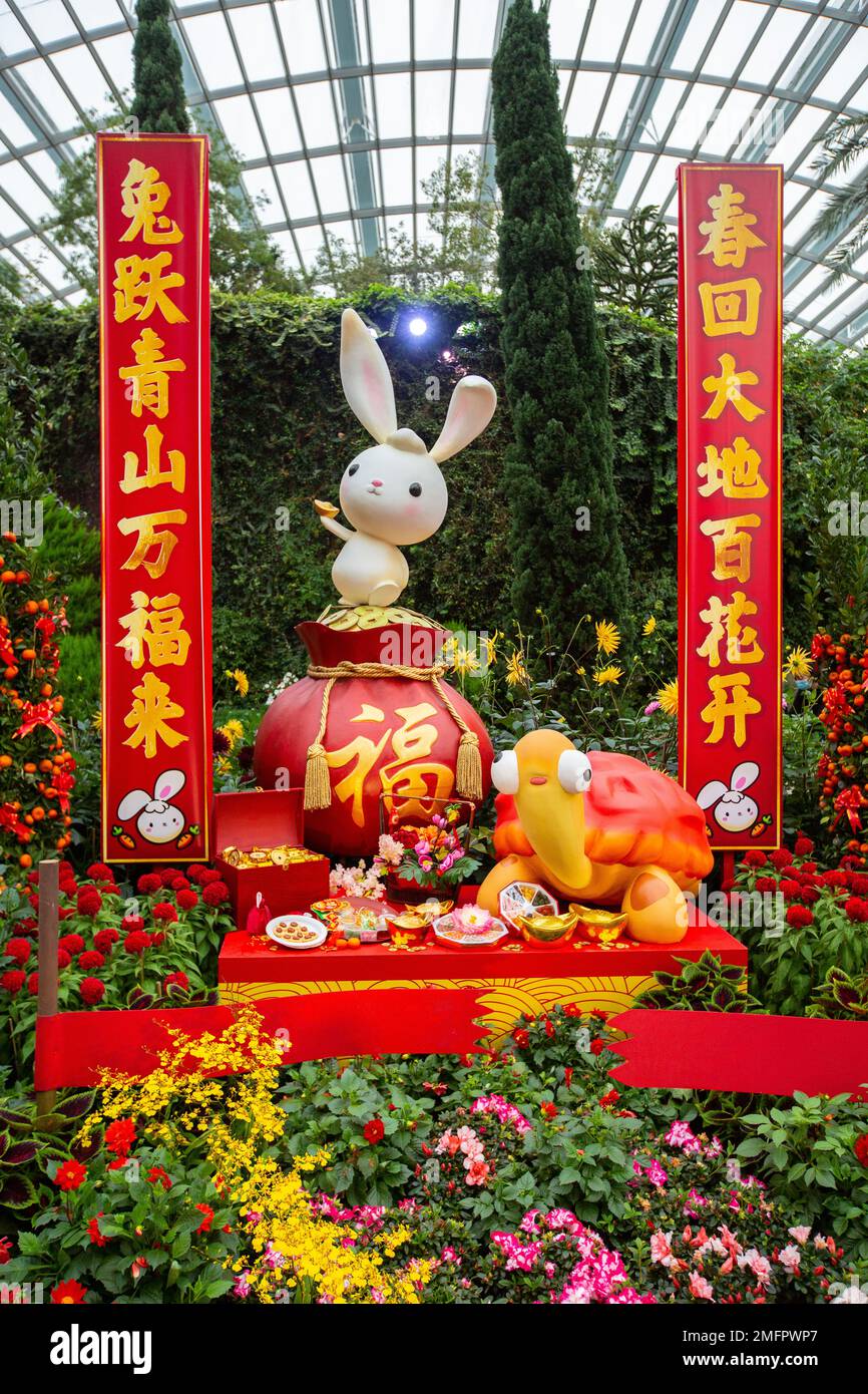 Chinesische Neujahrsdekoration von Kaninchen und Schildkröte, wunderschöne Blumen, rote Banner mit vielversprechenden Schriftzeichen. Gardens by the Bay, Singapur. Stockfoto