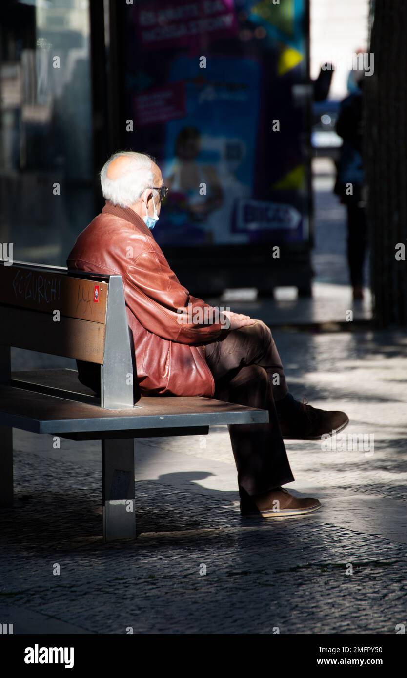 Älterer Mann sitzt auf einer Bank Stockfoto
