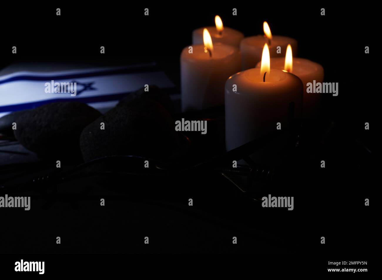 Brennende Kerze, Stacheldraht, Flagge Israels auf dunklem Hintergrund. Holocaust-Gedächtnisfeiertag Stockfoto