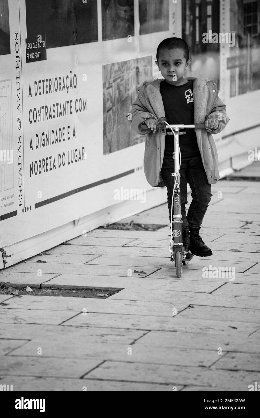 Kind auf dem Roller durch die Straßen der Stadt Stockfoto