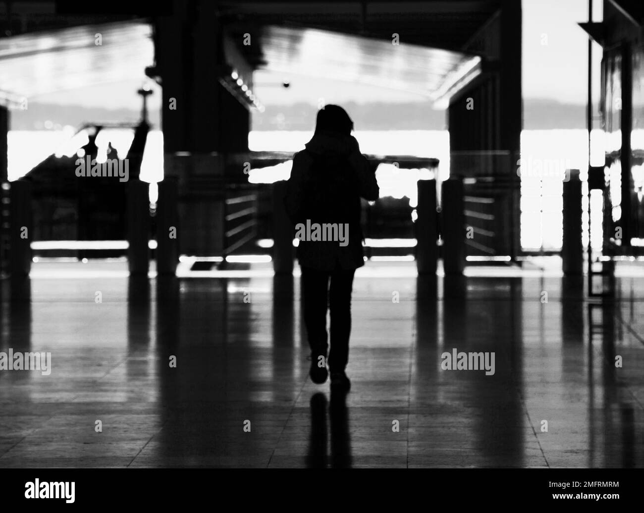 Frau in Silhouette spaziert durch den Bahnhof von Lissabon Stockfoto