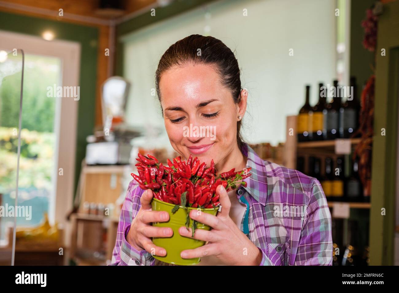 Ein wunderschönes Mädchen, das in einem Supermarkt Chili riecht - eine vegane, wunderschöne blonde Frau genießt den Geruch von Pfeffer, bevor sie im Laden buyngt Stockfoto