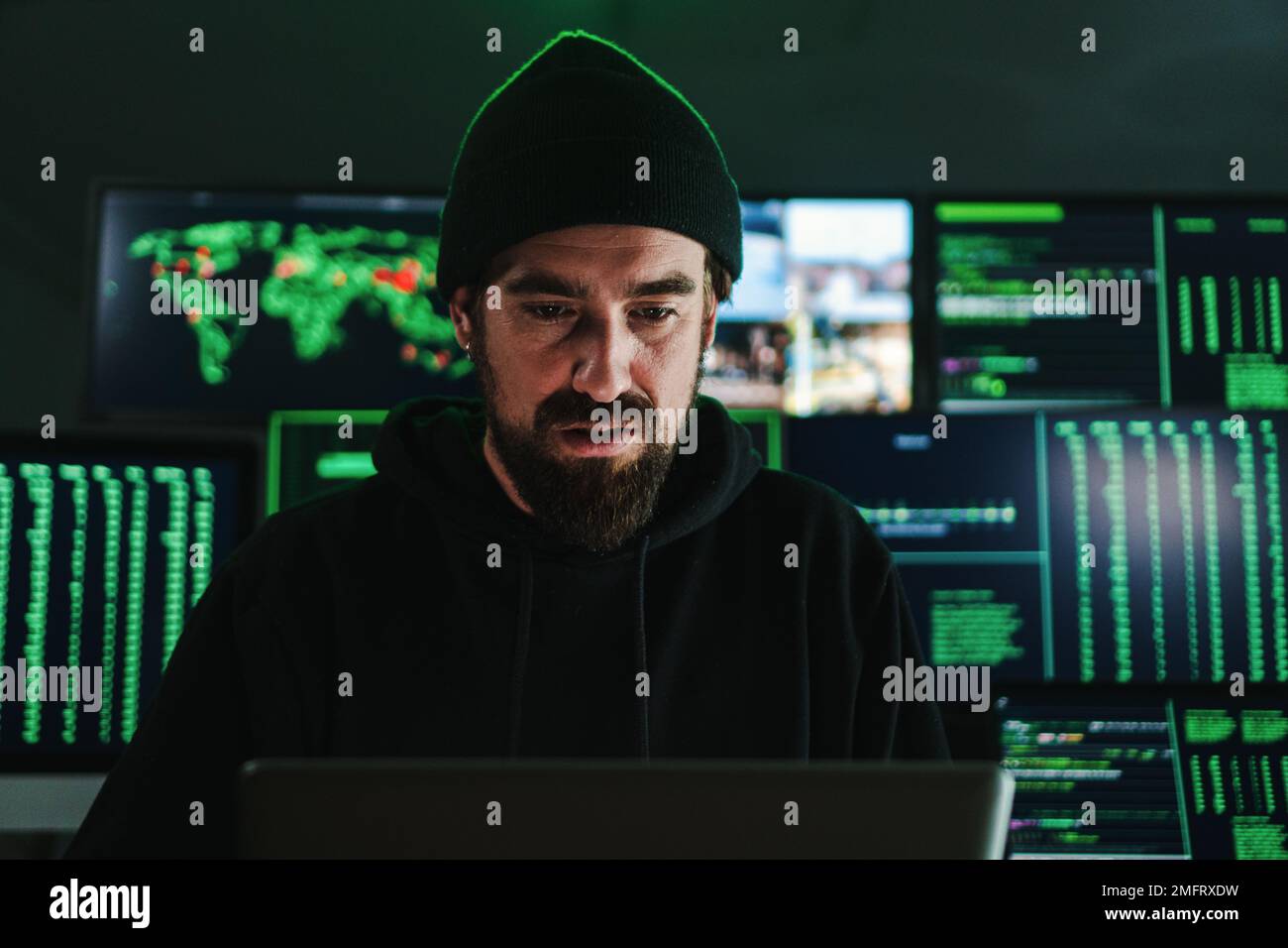 Ein krimineller Hacker programmiert einen Phishing-Virus, im Hintergrund viele Datenseiten. Ein Kaukasier, der an einem Internet-Firewall-System arbeitet. Cybersicherheitskonzept. Hochwertiges Foto Stockfoto