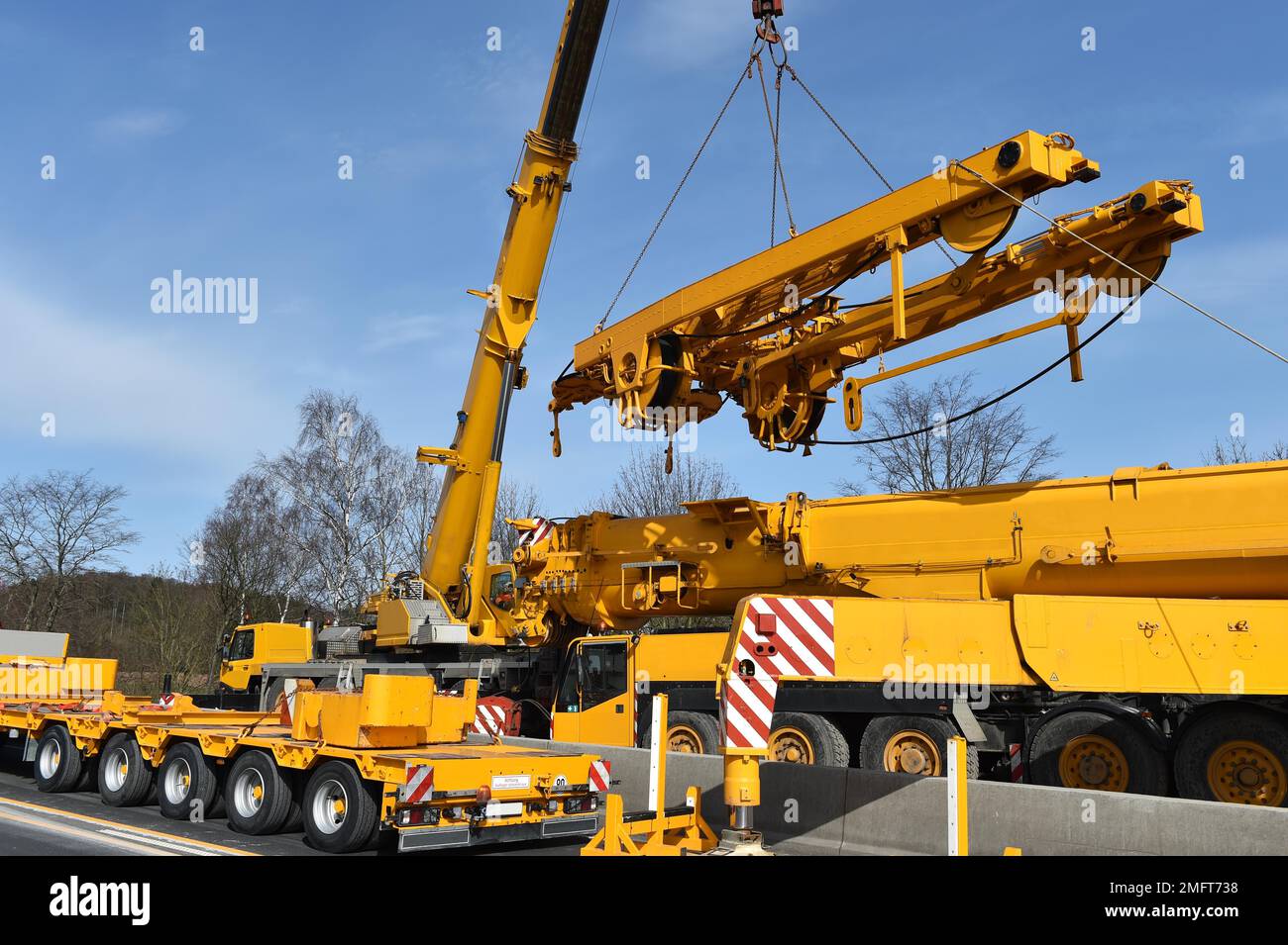 LKW-montierter Kran und Tieflader auf einer Baustelle in Deutschland Stockfoto