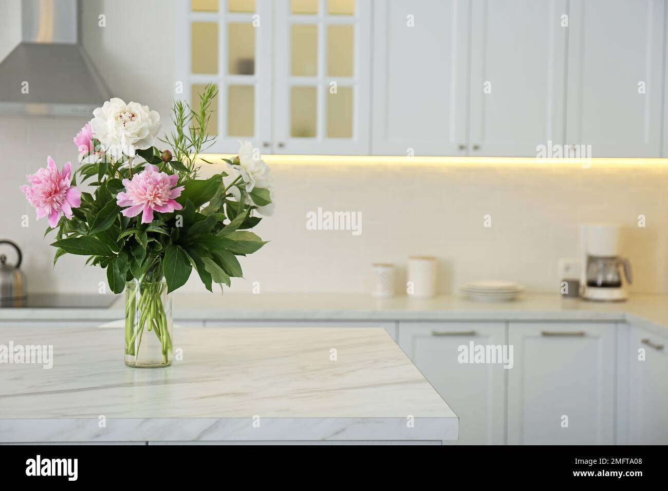 Pinkfarbene Blumenstrauß auf weißem Marmortisch im Küchenbereich Stockfoto