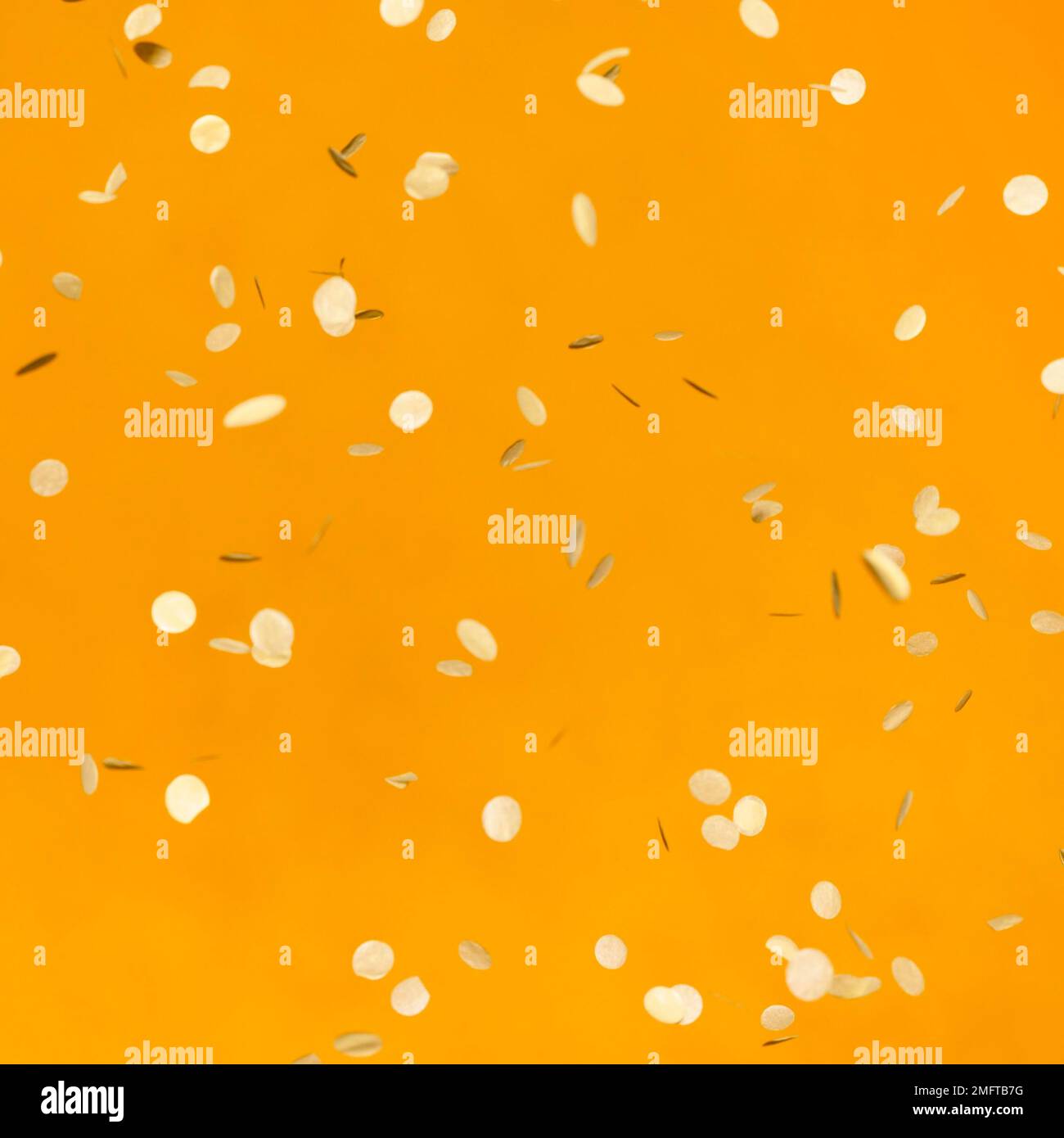 Arrangement goldene Partykonfetti orangefarbene Wand Stockfoto