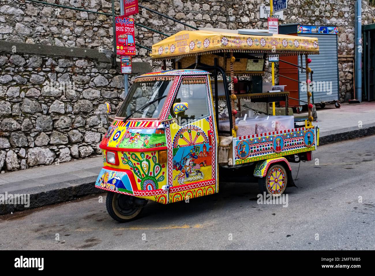 Farbenfroh dekorierter kleiner Lieferwagen Piaggio Ape, der Süßigkeiten im alten Teil des Touristenziels Taormina verkauft. Stockfoto