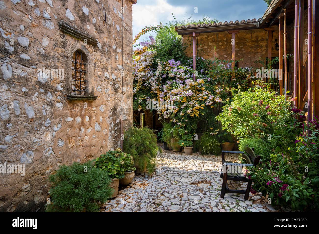 Innenhof mit Blumen, Steingebäude, Moni Agnountos Kloster, Peloponnes, Griechenland Stockfoto