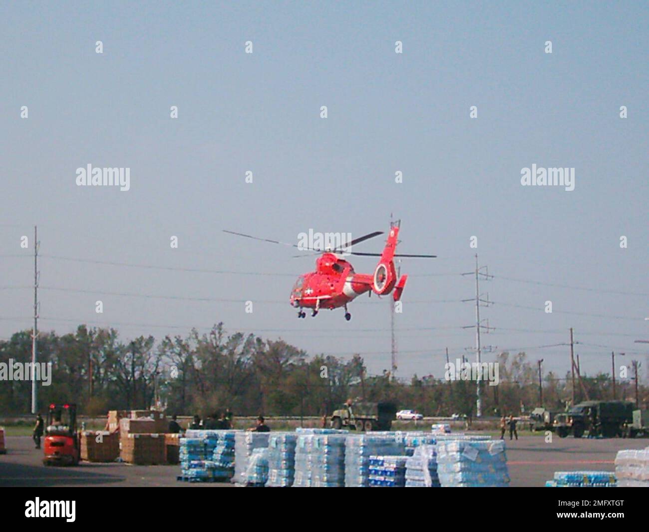 Flugzeuge - HH-65 Dolphin - 26-HK-54-10. HH-65 über militärischem Versorgungsgebiet mit Personal und Fahrzeugen. Hurrikan Katrina Stockfoto