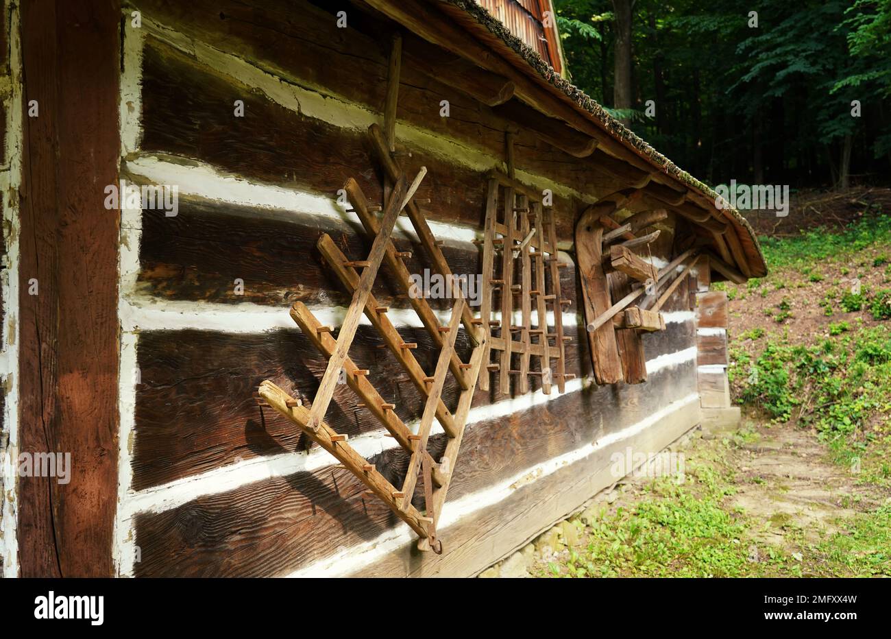 Sanok, Juli im Freilichtmuseum, alte landwirtschaftliche Werkzeuge an der Wand einer Holzhütte Stockfoto