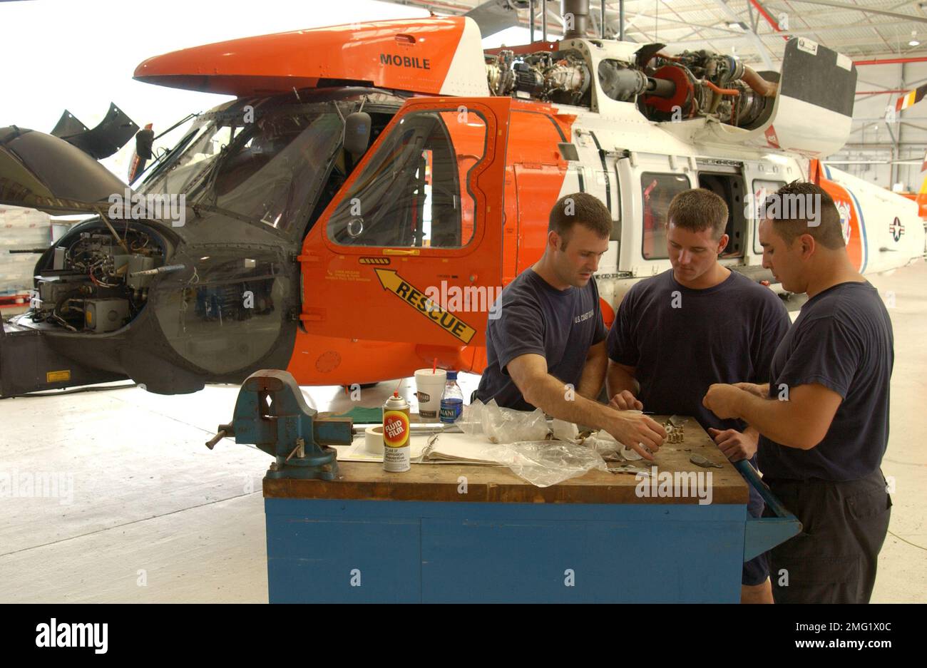 Strukturen der Küstenwache - Luftwaffenstützpunkte - Operationen - 26-HK-96-129. AIRSTA OPS--Küstenwachmänner, die in der Nähe von HH-60 in Hangar arbeiten (2). Hurrikan Katrina Stockfoto