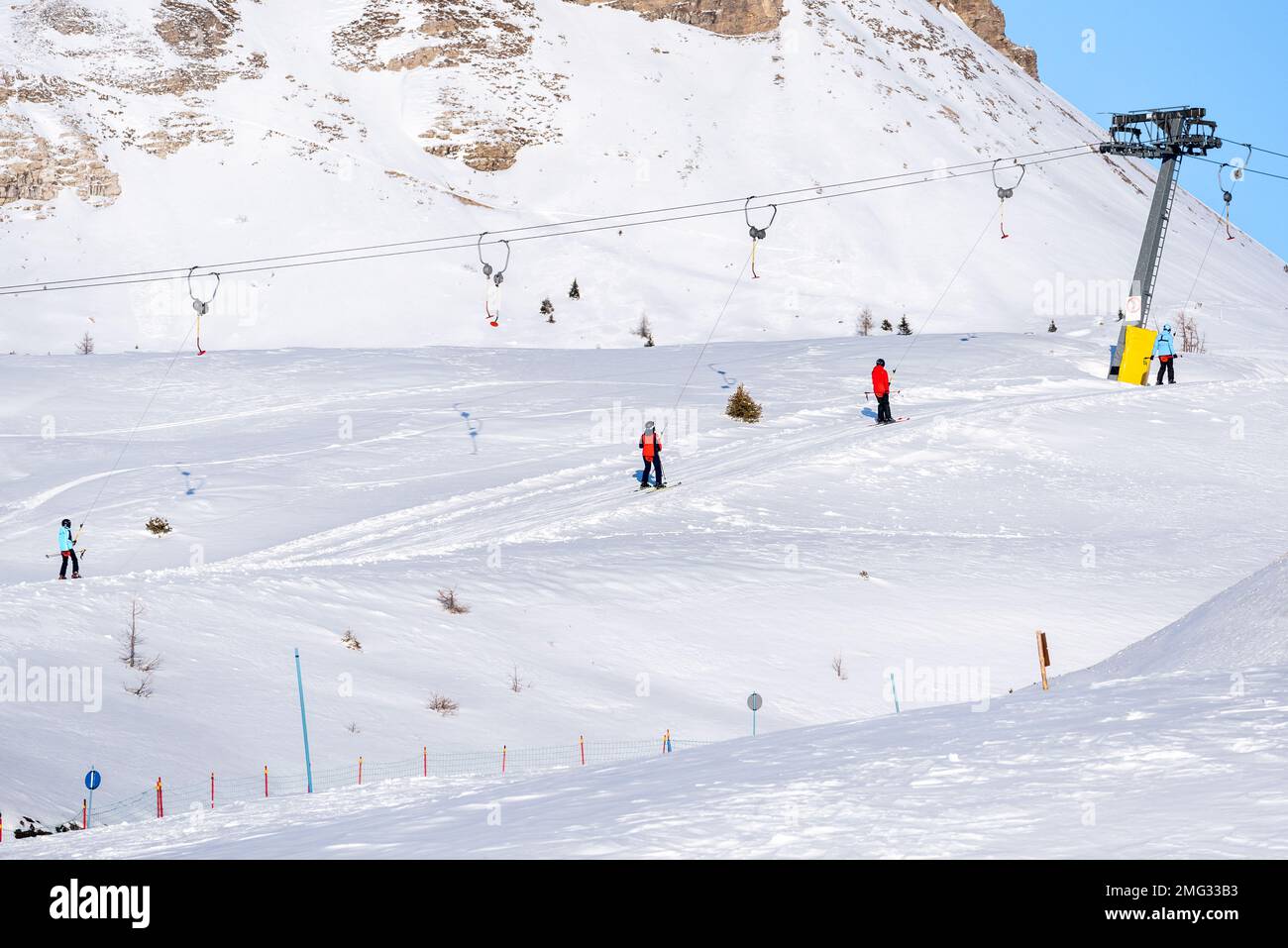 Skifahrer in hellen Skianzügen auf einem Skilift in den Alpen an einem sonnigen Wintertag Stockfoto