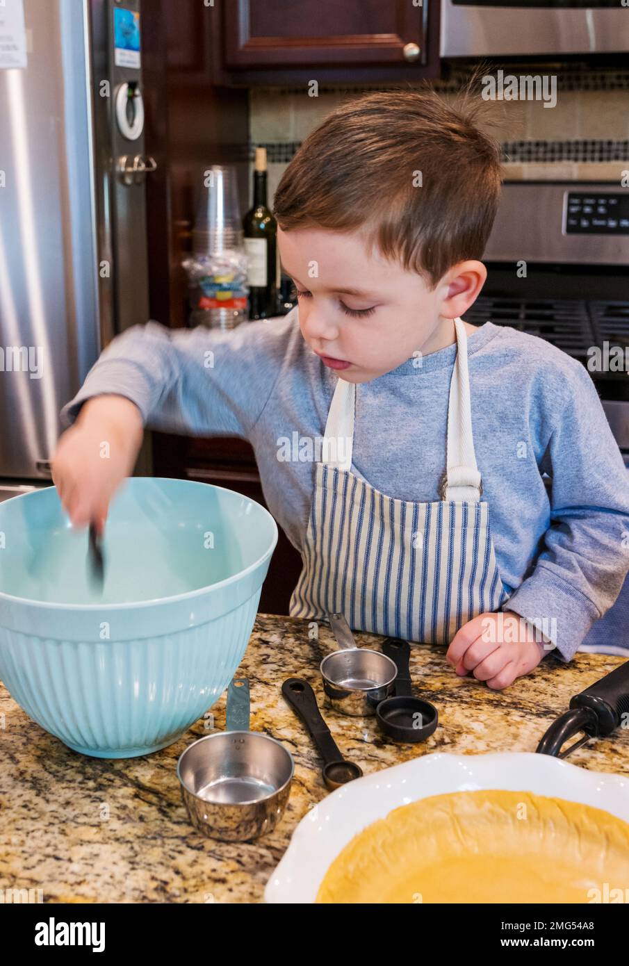 Drei Jahre alter Junge, der Großmutter beim Backen eines Apfelkuchen an Thanksgiving hilft; Philadelphia; Pennsylvania; USA Stockfoto