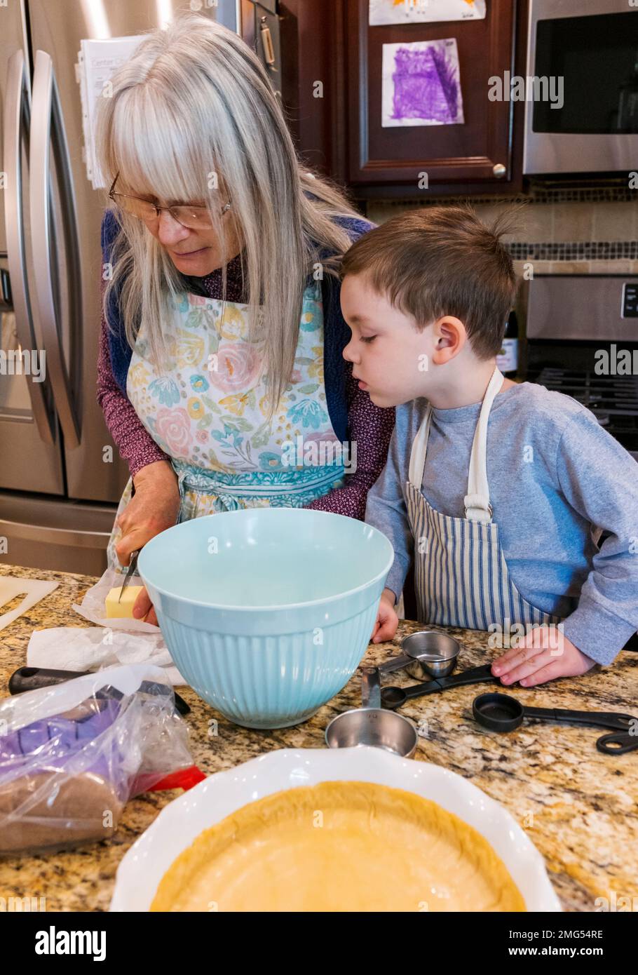 Drei Jahre alter Junge, der Großmutter beim Backen eines Apfelkuchen an Thanksgiving hilft; Philadelphia; Pennsylvania; USA Stockfoto