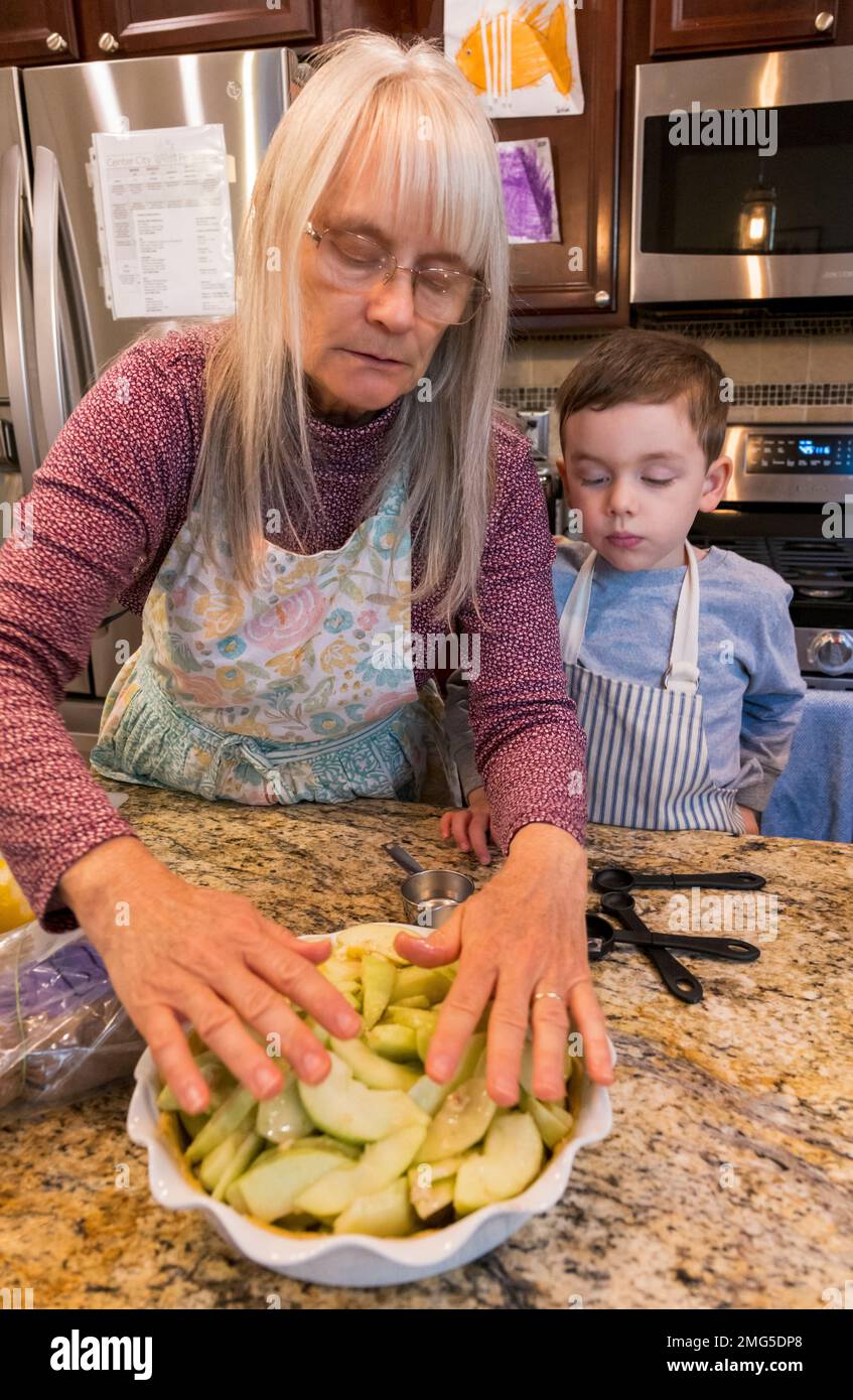 Drei Jahre alter Junge, der Großmutter beim Backen eines Apfelkuchen an Thanksgiving hilft; Philadelphia; Pennsylvania; USA Stockfoto