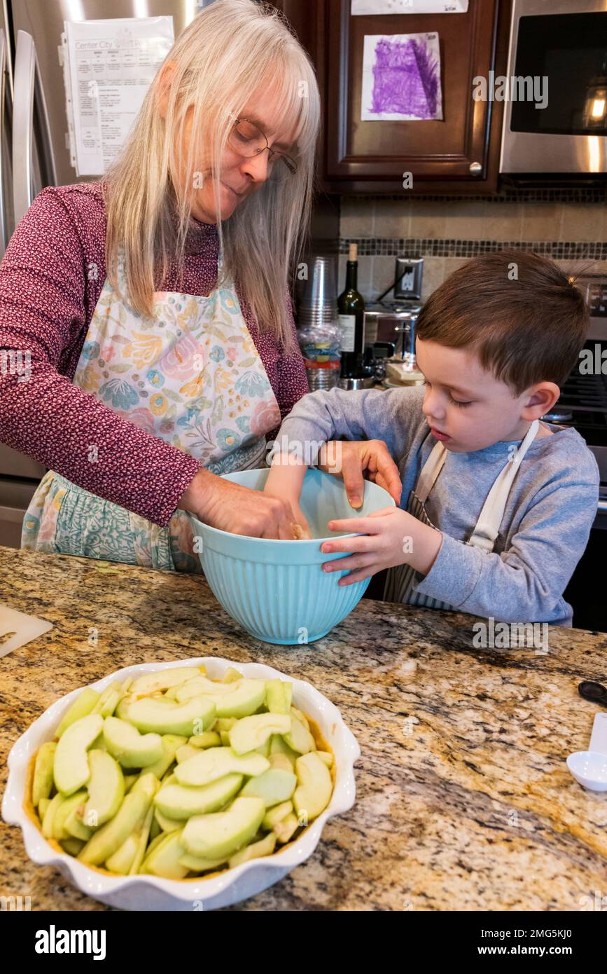 Drei Jahre alter Junge, der Großmutter beim Backen eines Apfelkuchen an Thanksgiving hilft; Philadelphia; Pennsylvania; USA Stockfoto