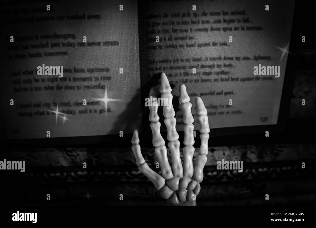 Dieses Skelett benutzt ihre Finger, um die Wörter zu umreißen, die in einem alten Zauberbuch gelesen werden. Stockfoto