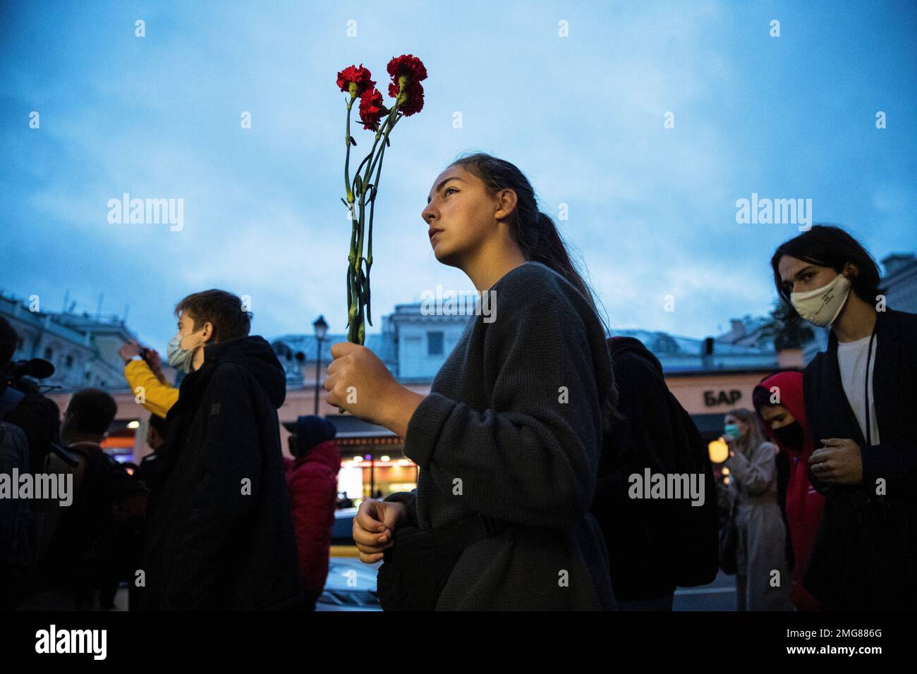 A woman holds flowers as people, some of them ethnic Belarusians, gather to support Belarusian opposition in front of Belarusian Embassy in Moscow, Russia, Thursday, Aug. 13, 2020. Crowds of protesters in Belarus swarmed the streets and thousands of workers rallied outside industrial plants to denounce a police crackdown on demonstrations over a disputed election that extended the 26-year rule of authoritarian President Alexander Lukashenko. (AP Photo/Pavel Golovkin) Stockfoto