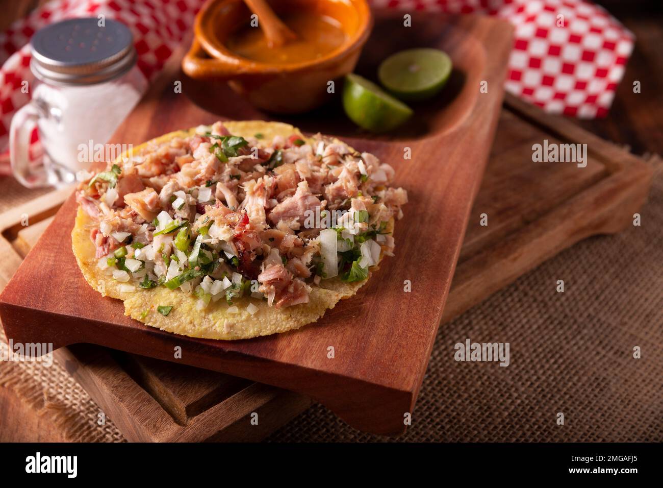 Taco de Carnitas. Maismehl-Tortilla mit frittiertem Schweinefleisch. Traditionelle mexikanische Vorspeise, begleitet von Koriander, Zwiebel und heißer Sauce. Stockfoto