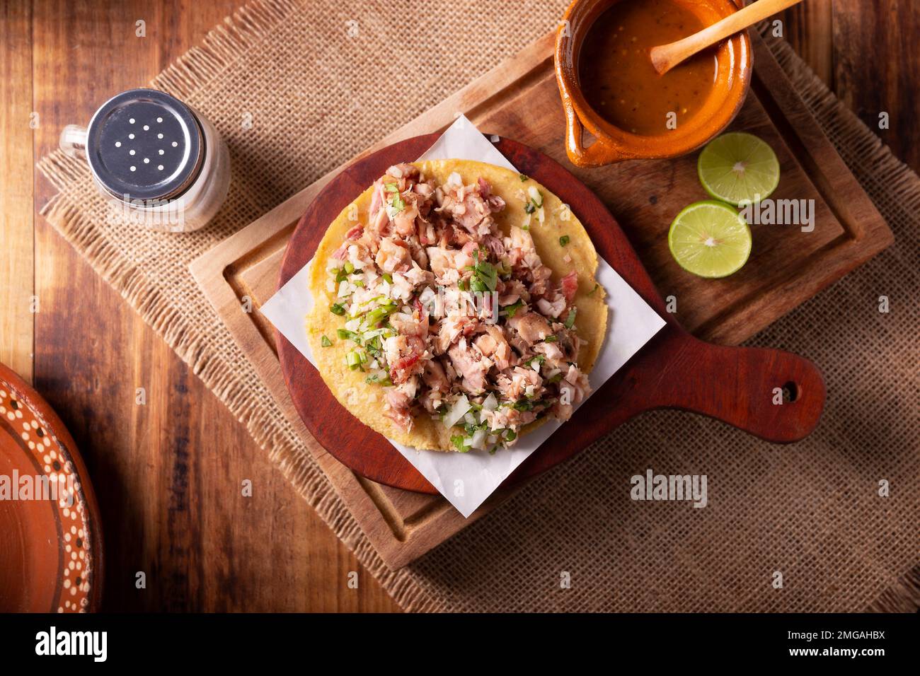 Taco de Carnitas. Maismehl-Tortilla mit frittiertem Schweinefleisch. Traditionelle mexikanische Vorspeise, begleitet von Koriander, Zwiebel und heißer Sauce. Stockfoto