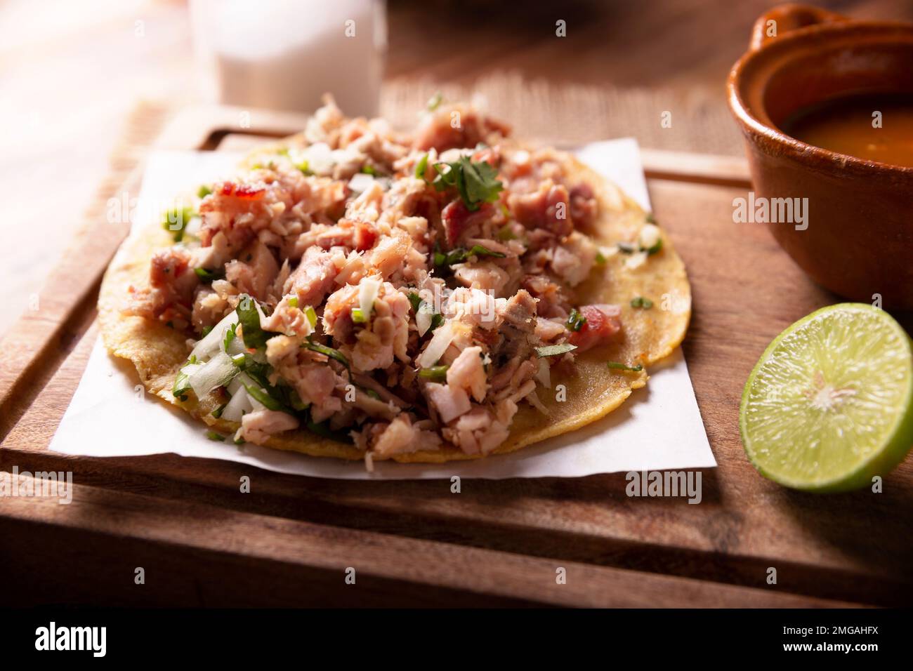 Taco de Carnitas. Maismehl-Tortilla mit frittiertem Schweinefleisch. Traditionelle mexikanische Vorspeise, begleitet von Koriander, Zwiebel und heißer Sauce. Stockfoto