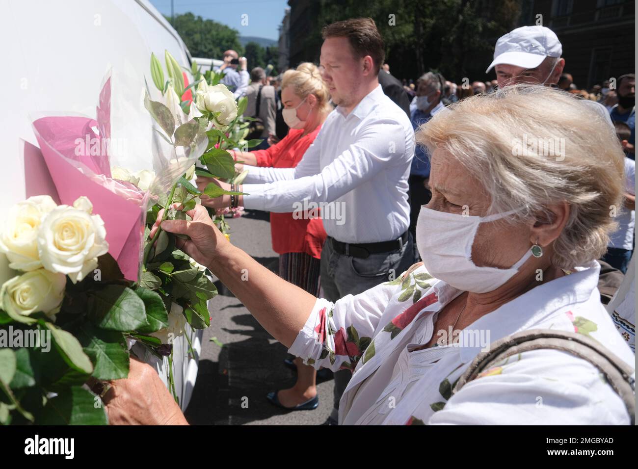 People place flowers on vans as hundreds of people turned out in Sarajevo's main street Thursday, July 9, 2020, to pay respects to eight victims of the Srebrenica massacre as three white vans carried their coffins to a final resting place. The remains of the men and boys, found in mass graves and identified through DNA analysis, will be buried in Srebrenica on Saturday, the 25th anniversary of the massacre, next to 6,610 previously found victims. (AP Photo/Kemal Softic) Stockfoto