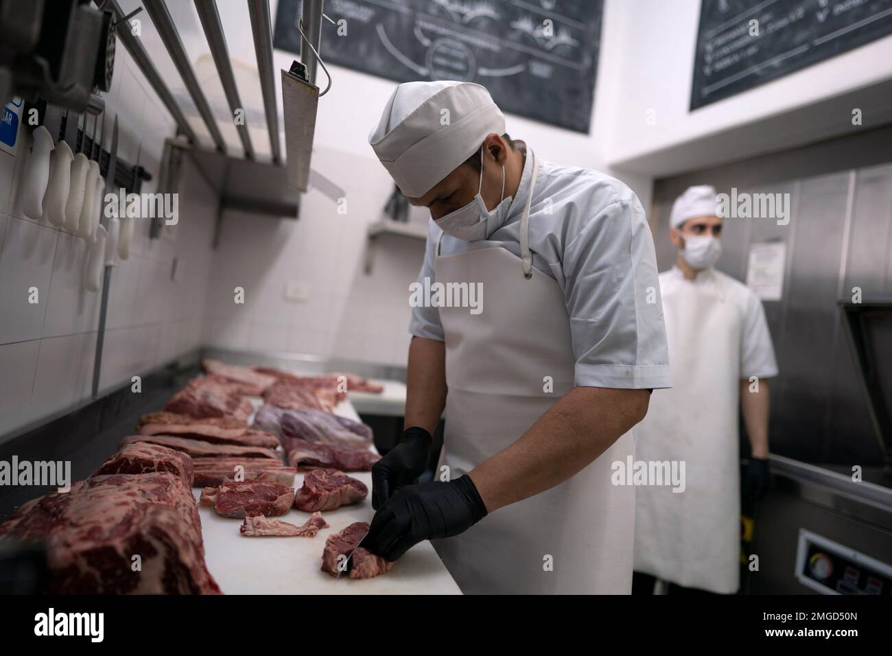 In this June 12, 2020 photo, a butcher cuts meat at Don Julio butcher's shop in Buenos Aires, Argentina. Don Julio's steakhouse turned itself into a high-end delivery butcher shop after the restaurant was forced to closed on March 20th due to the COVID-19 pandemic. (AP Photo/Victor R. Caivano) Stockfoto
