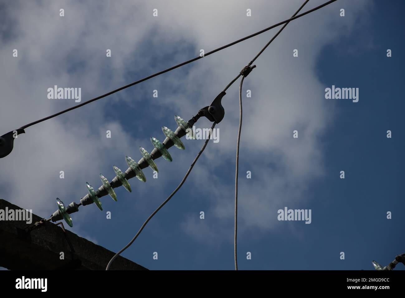 Stromleitungen im Hintergrund von Nahaufnahmen mit blauem Himmel. Elektrische Nabe an der Stange. Elektrizitätsanlage mit Kopierraum. Hochspannungsleitungen am Himmel. Stockfoto