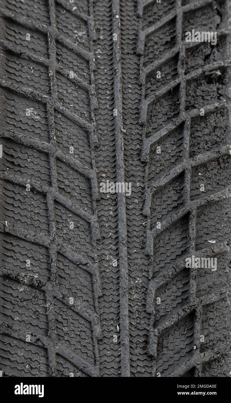 Spuren von Reifenprofilen im Boden. Muster. Dunkler abstrakter Hintergrund. Aufdruck der Räder. Strukturierter Boden. Reifen zeichnen. Stockfoto