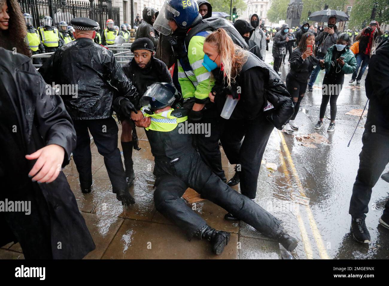 A police officer who was injured when falling of a horse during scuffles with demonstrators at Downing Street during a Black Lives Matter march in London, Saturday, June 6, 2020, is dragged by colleagues, as people protest against the killing of George Floyd by police officers in Minneapolis, USA. Floyd, a black man, died after he was restrained by Minneapolis police while in custody on May 25 in Minnesota. (AP Photo/Frank Augstein) Stockfoto