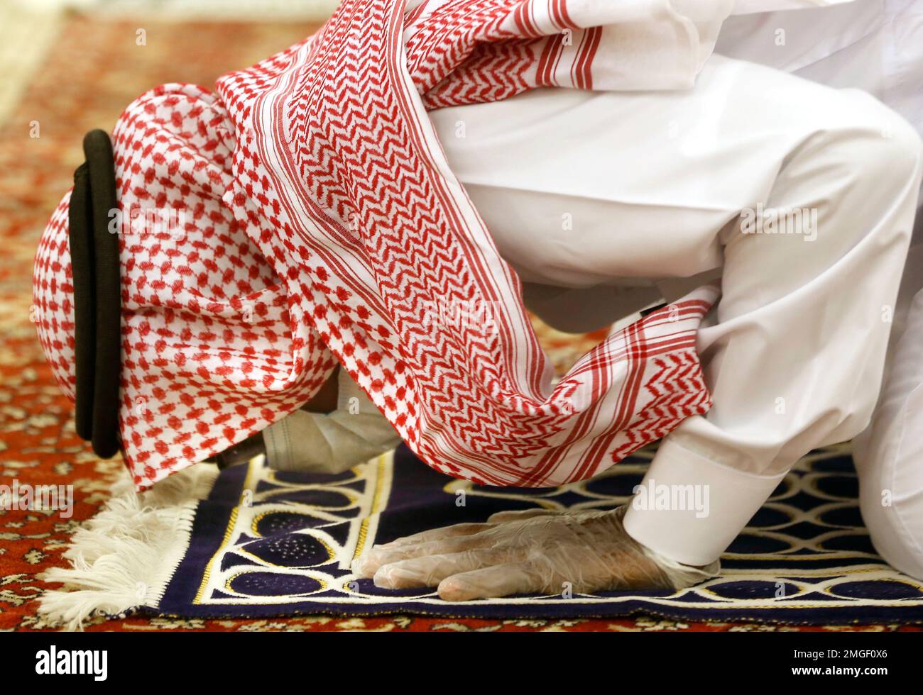 A Saudi worshipper wearing a face mask and gloves to prevent the spread ...