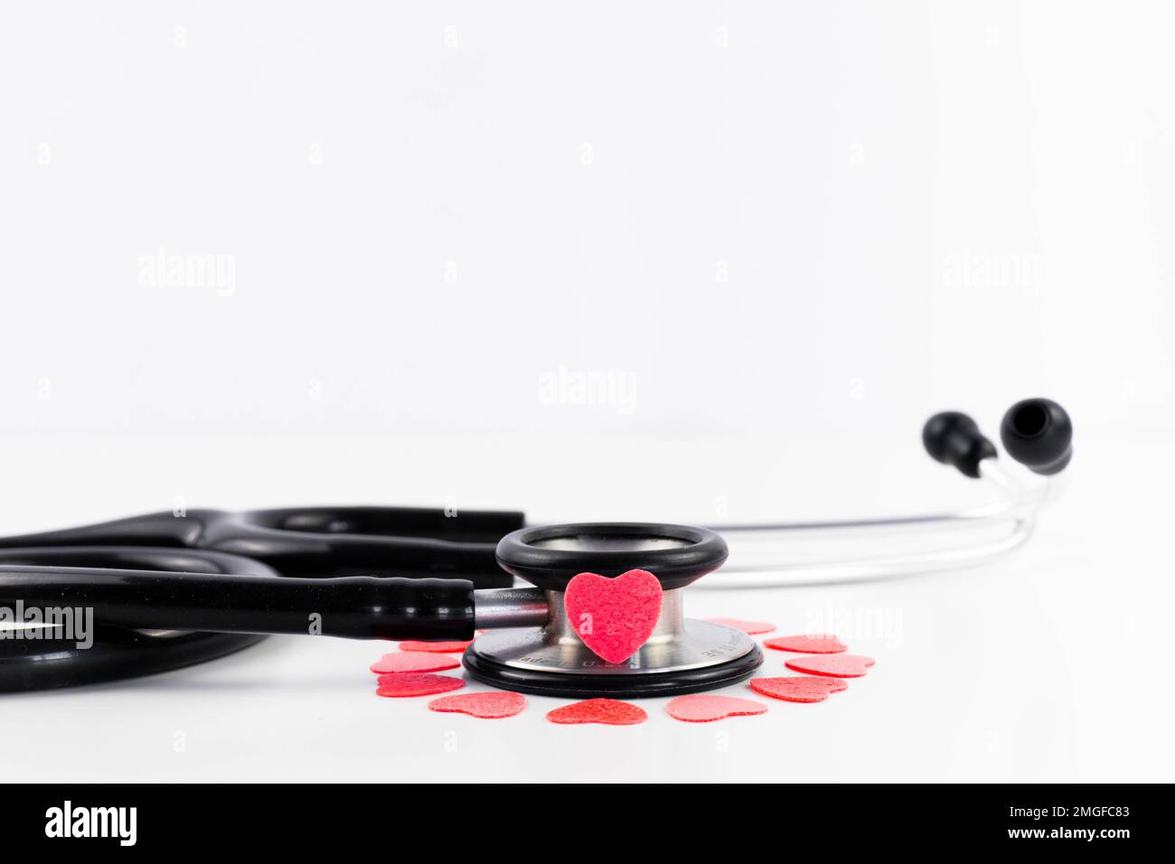 Nahaufnahme-Stethoskop mit rosa und roten Herzen auf weißem Hintergrund und Kopierbereich. Arzt liebt Medizin, Herzkrankheiten und Kardiologie. Stockfoto