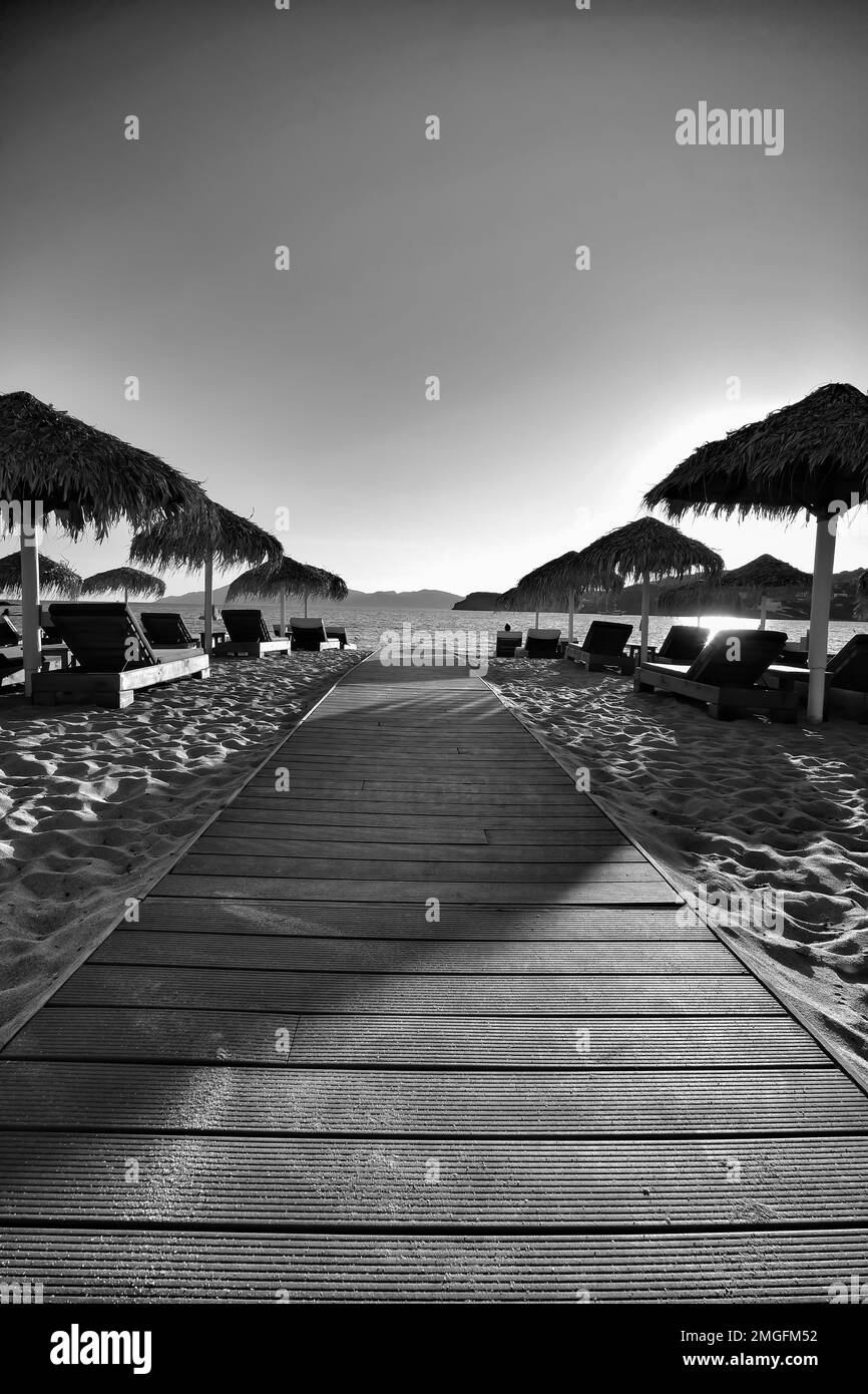IOS, Griechenland - 3. Juni 2021 : Blick auf einen hölzernen Pfad zum atemberaubenden Strand von Mylopotas in iOS Griechenland in Schwarz-Weiß Stockfoto