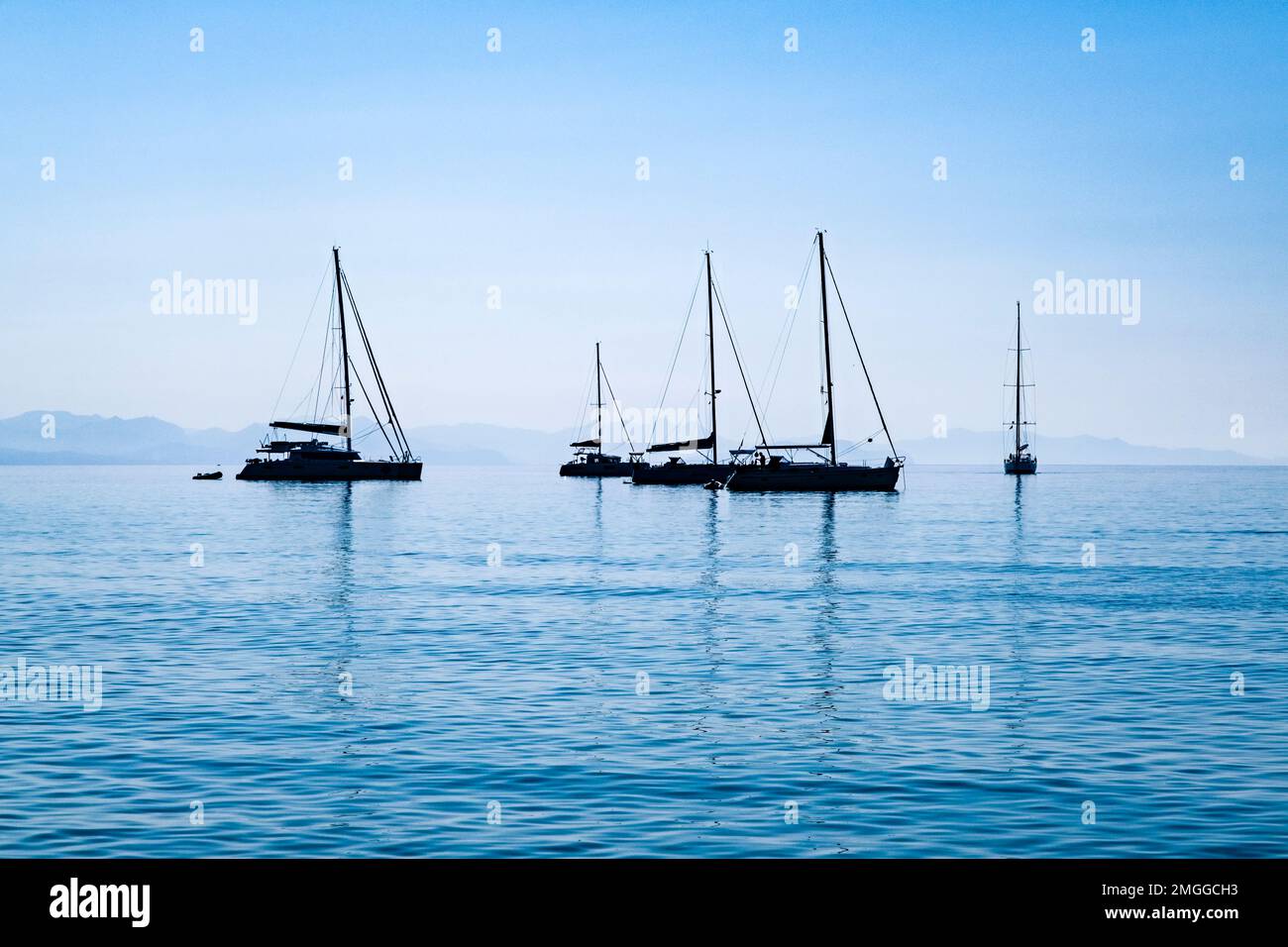 Fünf Segelboote ankern vor der Küste der mittelalterlichen Stadt Cefalu. Stockfoto