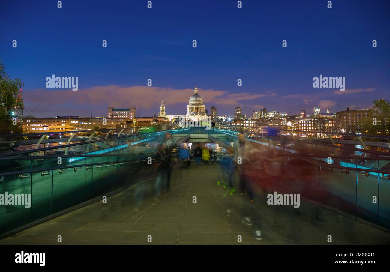 London, Großbritannien - St. Paul's Cathedral und Millennium Bridge nach Sonnenuntergang mit verschwommenen Menschenmassen und klarem blauen Himmel Stockfoto