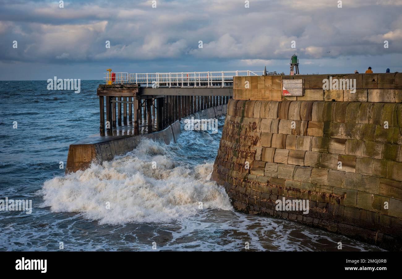 Große Wellen stürzen sich durch die Hafeneingangspiers in Whitby, North Yorkshire, Großbritannien Stockfoto