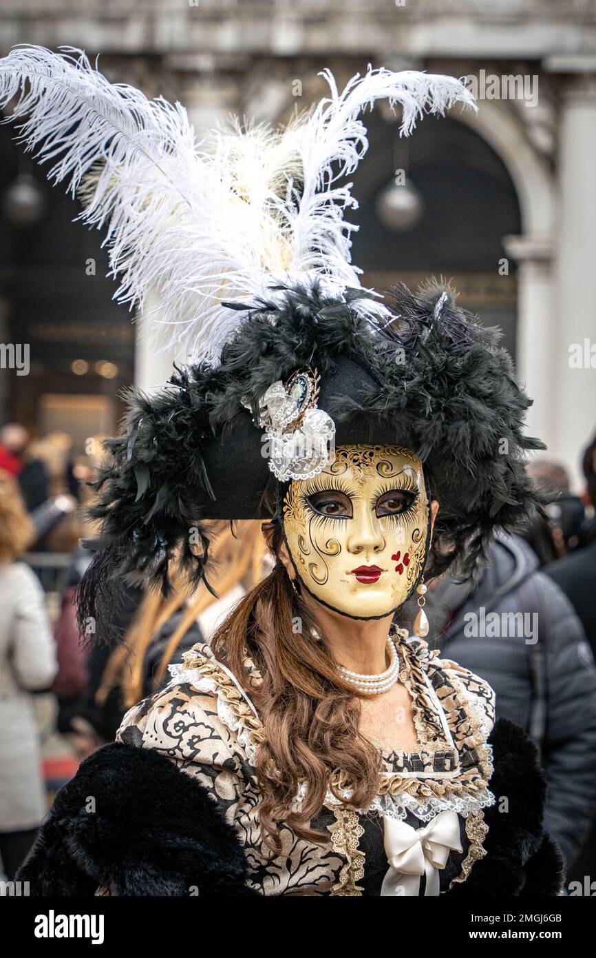 Eine Frau in einem dunklen mittelalterlichen Kostüm, einer weiblichen Karnevalsmaske und einem großen schicken Hut mit Federn auf dem Karneval in Venedig, Italien Stockfoto
