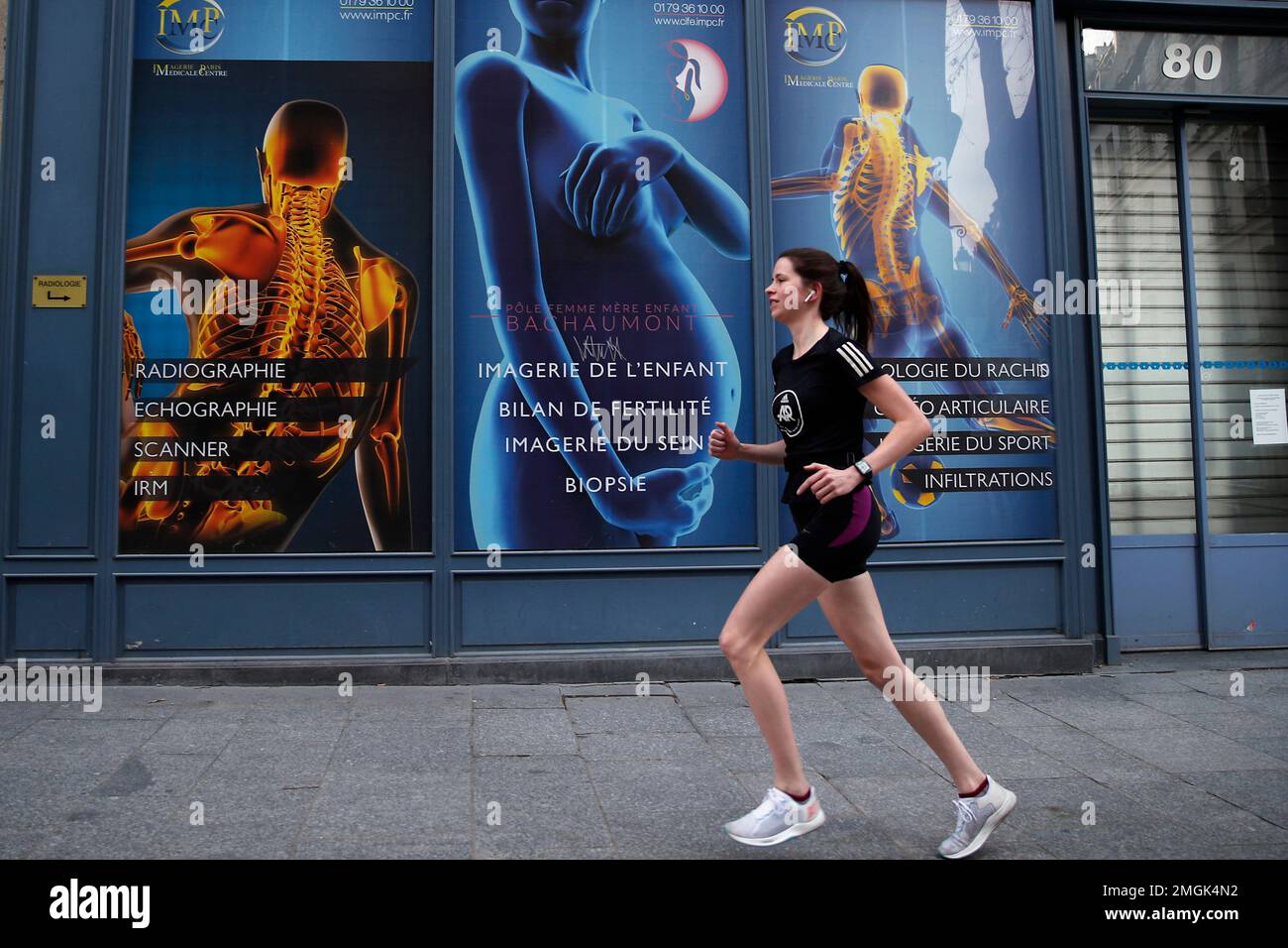 French IT consultant, Amelie Desroziers, 25, goes jogging for her daily one hour exercise during a nationwide confinement to counter the Covid-19, in Paris, Tuesday, April 7, 2020. The new coronavirus causes mild or moderate symptoms for most people, but for some, especially older adults and people with existing health problems, it can cause more severe illness or death. (AP Photo/Francois Mori) Stockfoto